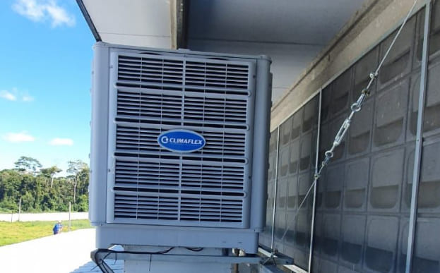 Foto ilustrativa de um climatizador evaporativo do lado de fora de um galpão