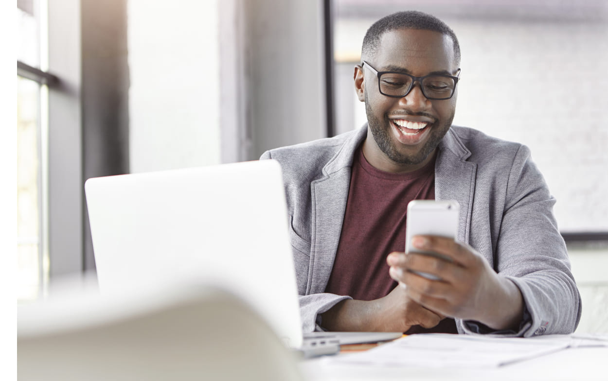 Imagem ilustrativa de um homem sorrindo enquanto mexe no celular